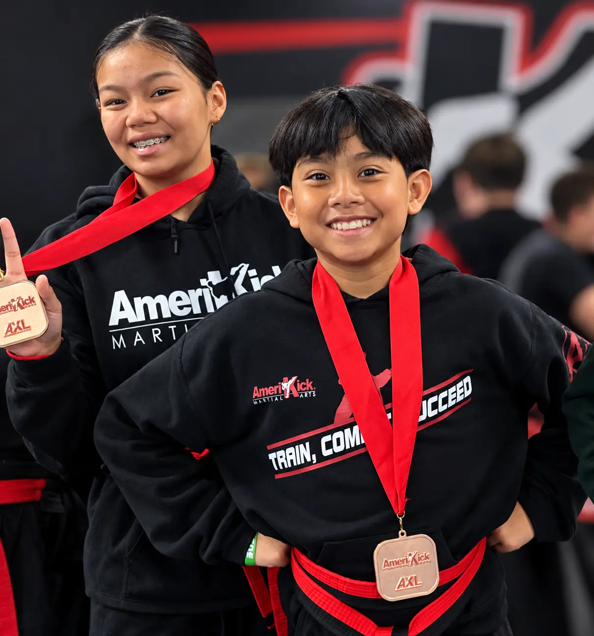 Two smiling AmeriKick students celebrating their medals