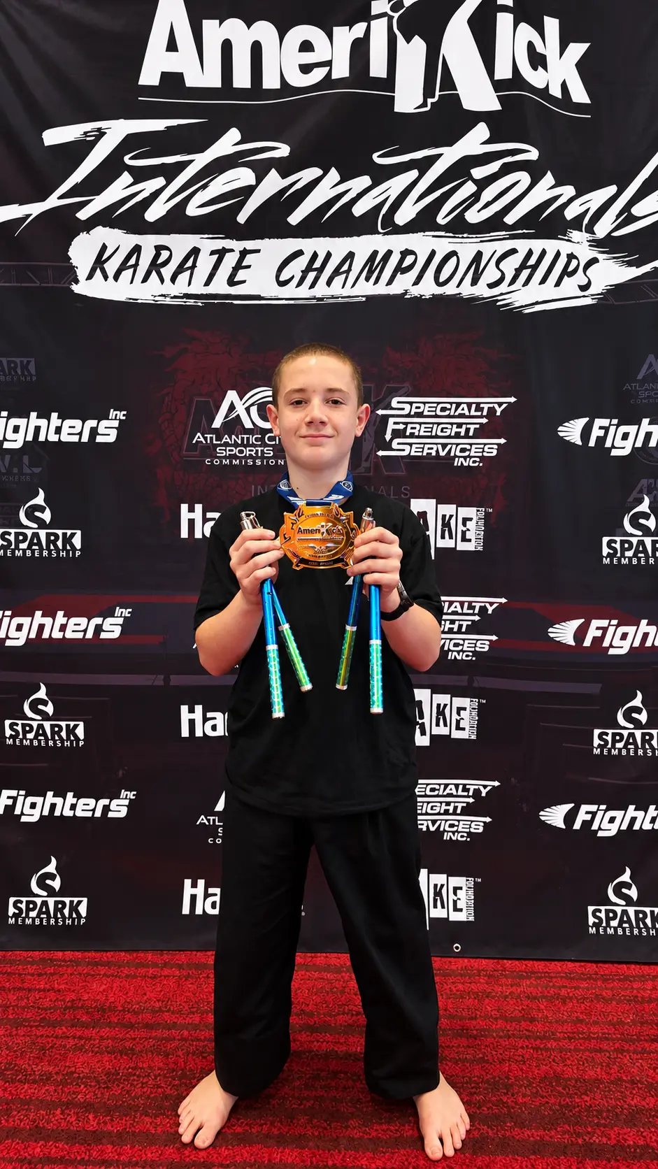 AmeriKick student displaying a championship medal and training equipment